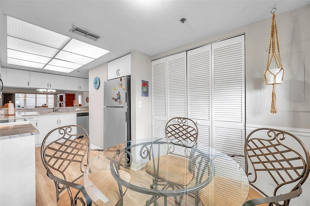 dining space with light wood-type flooring and sink