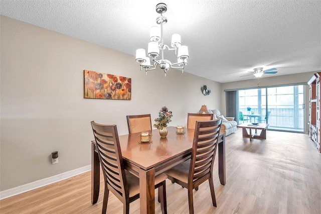 dining room featuring ceiling fan with notable chandelier, light wood-type flooring, and a textured ceiling