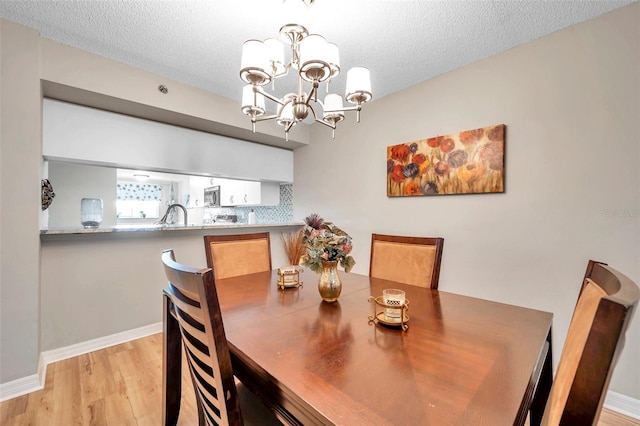 dining space with light wood-type flooring, a chandelier, and a textured ceiling