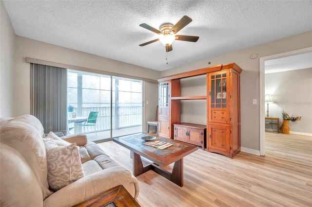 living room featuring light hardwood / wood-style floors, ceiling fan, and a textured ceiling