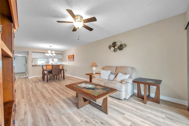 living room with light wood-type flooring, ceiling fan with notable chandelier, and a textured ceiling