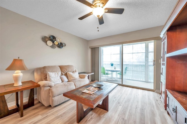 living room with a textured ceiling, ceiling fan, and light hardwood / wood-style flooring