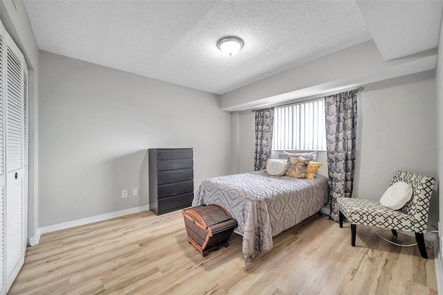 bedroom featuring a textured ceiling, a closet, and light hardwood / wood-style floors