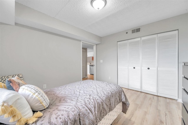 bedroom featuring light wood-type flooring, a closet, and a textured ceiling