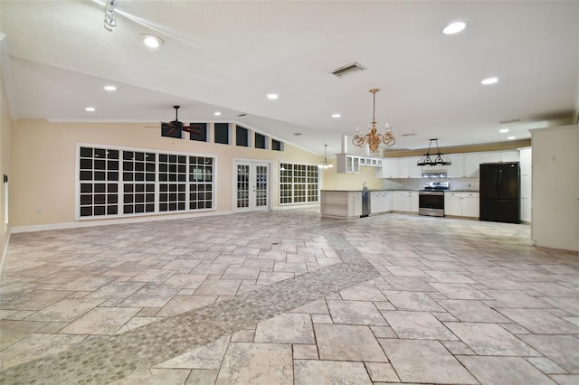 interior space featuring open floor plan, stone tile flooring, stainless steel electric range, and freestanding refrigerator