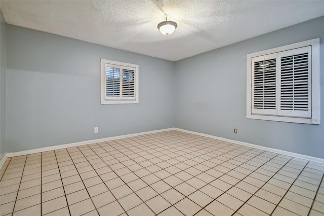 unfurnished room featuring a textured ceiling and baseboards