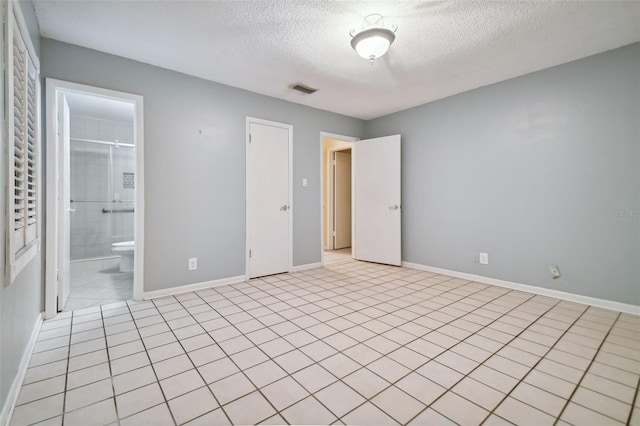 unfurnished bedroom featuring a textured ceiling, ensuite bathroom, visible vents, and baseboards