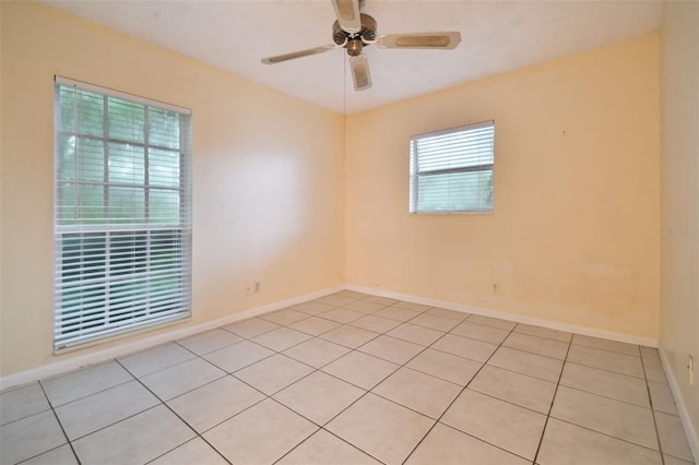 unfurnished room featuring ceiling fan, light tile patterned floors, and baseboards