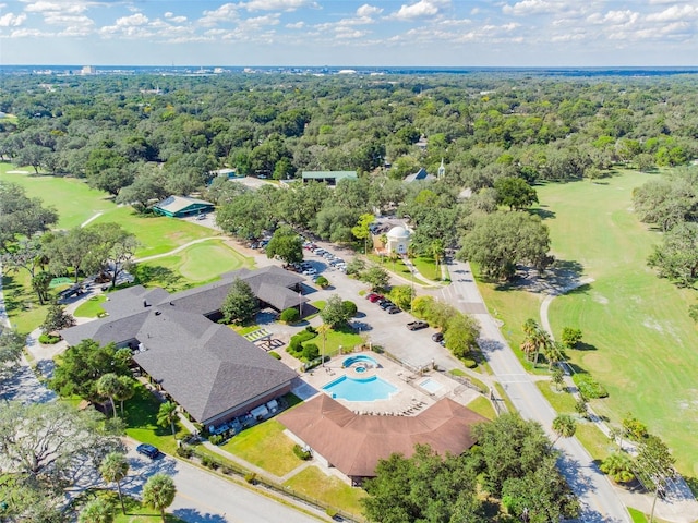 drone / aerial view featuring view of golf course and a view of trees