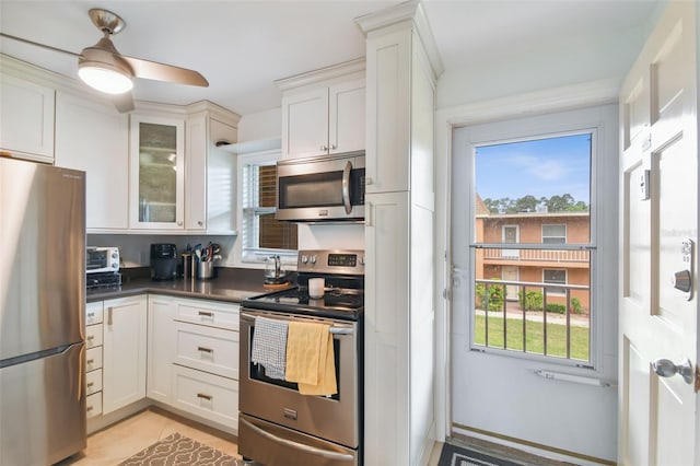 kitchen with appliances with stainless steel finishes, dark countertops, white cabinetry, and plenty of natural light