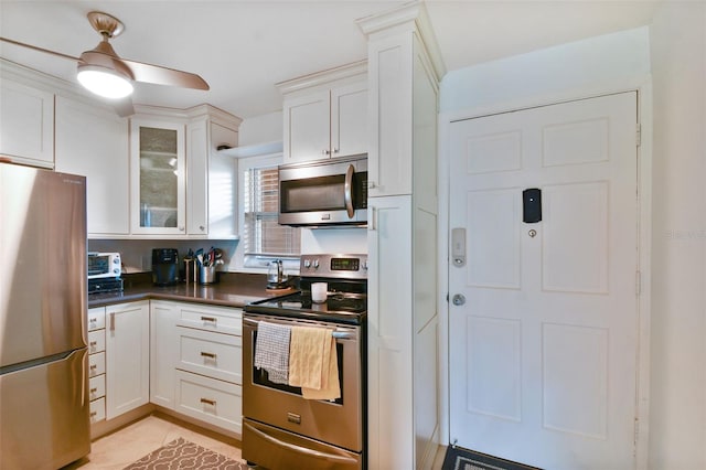 kitchen with stainless steel appliances, ceiling fan, white cabinetry, and light tile patterned flooring