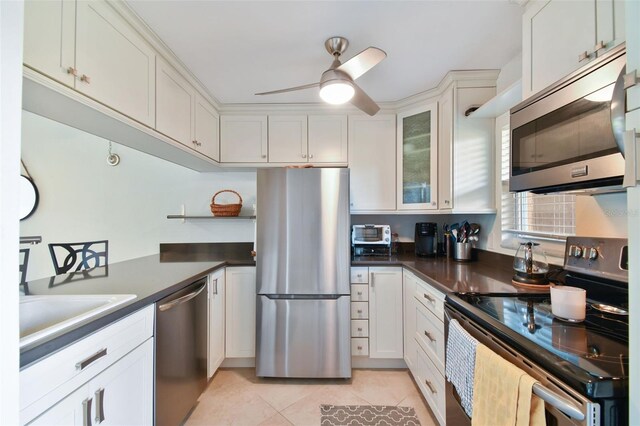 kitchen featuring white cabinets, ceiling fan, light tile patterned floors, and stainless steel appliances