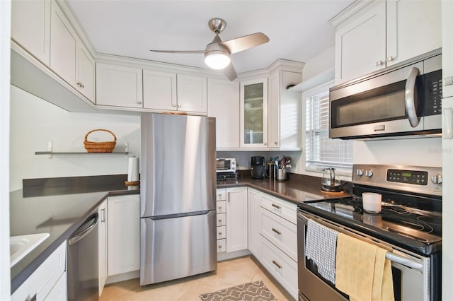 kitchen with ceiling fan, light tile patterned floors, appliances with stainless steel finishes, and white cabinetry