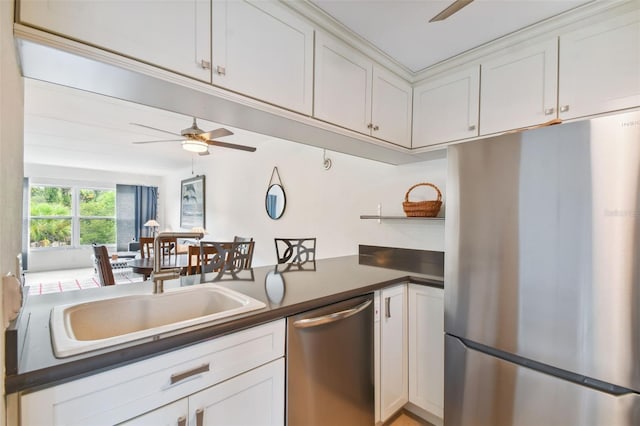 kitchen with appliances with stainless steel finishes, white cabinetry, sink, kitchen peninsula, and ceiling fan