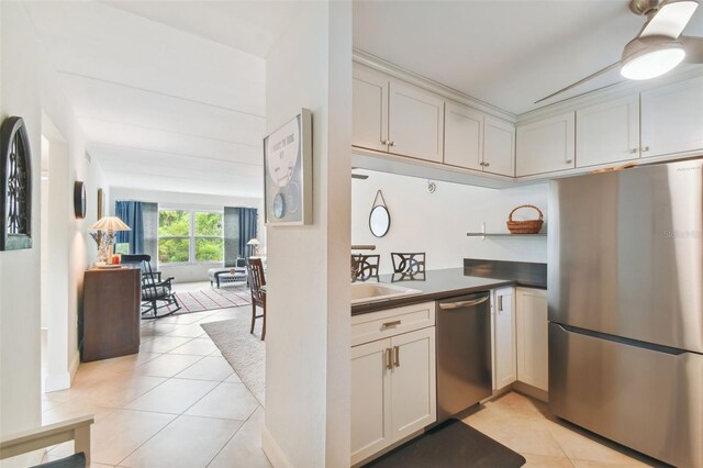 kitchen featuring dark countertops, appliances with stainless steel finishes, light tile patterned flooring, and a sink