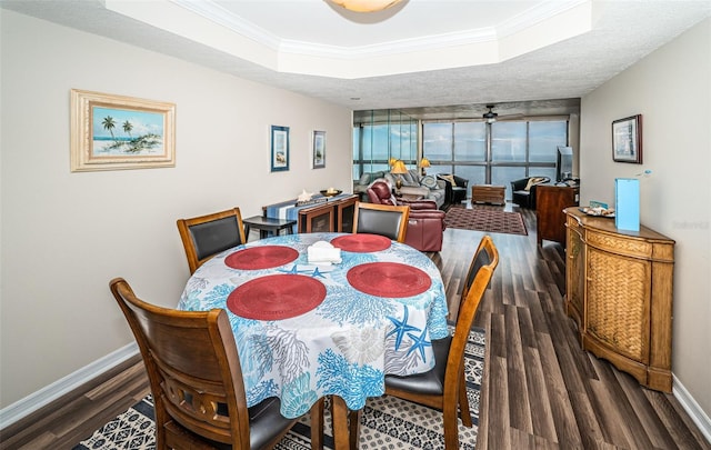 dining area featuring crown molding, dark wood-type flooring, a raised ceiling, and ceiling fan