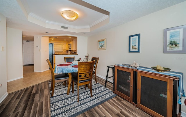 dining space featuring ornamental molding, dark hardwood / wood-style floors, and a tray ceiling