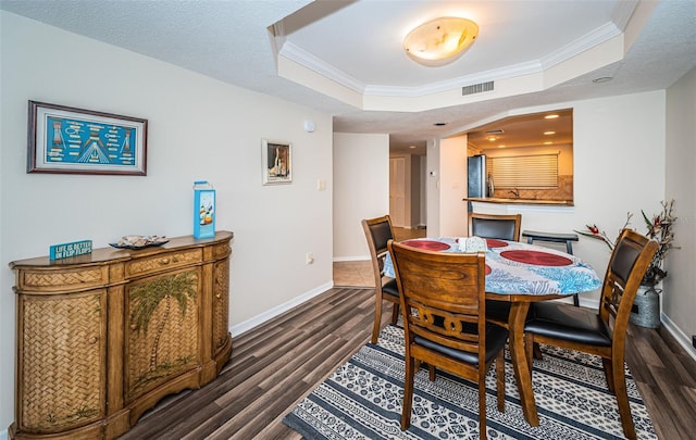 dining room with a tray ceiling, crown molding, and dark hardwood / wood-style flooring