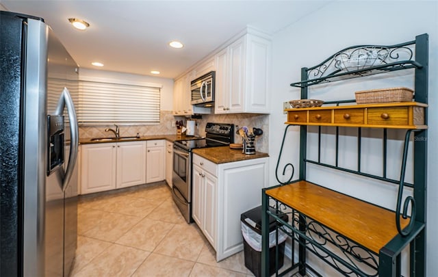 kitchen with white cabinets, appliances with stainless steel finishes, light tile patterned floors, and decorative backsplash