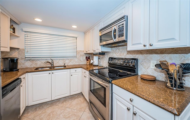 kitchen with dark stone counters, appliances with stainless steel finishes, sink, and white cabinets