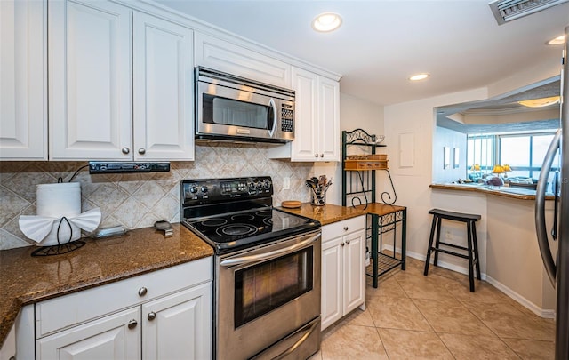 kitchen with white cabinets, stainless steel appliances, and dark stone counters