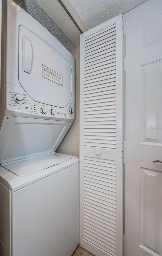 washroom featuring a textured ceiling and stacked washer and clothes dryer