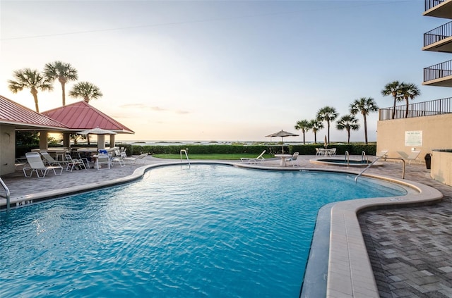 pool at dusk featuring a patio