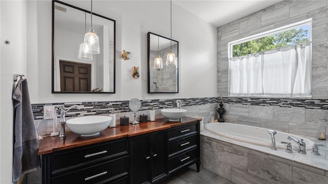 bathroom with vanity, tiled tub, and tile walls