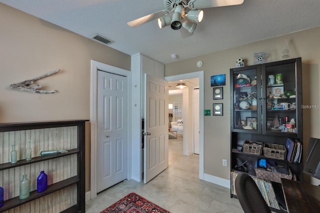 interior space featuring ceiling fan and a textured ceiling