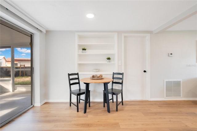 dining space featuring built in shelves and light hardwood / wood-style flooring