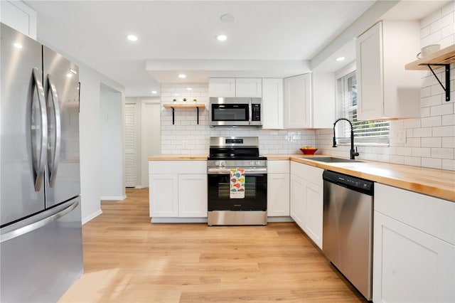 kitchen with white cabinetry, light wood-type flooring, butcher block counters, and appliances with stainless steel finishes