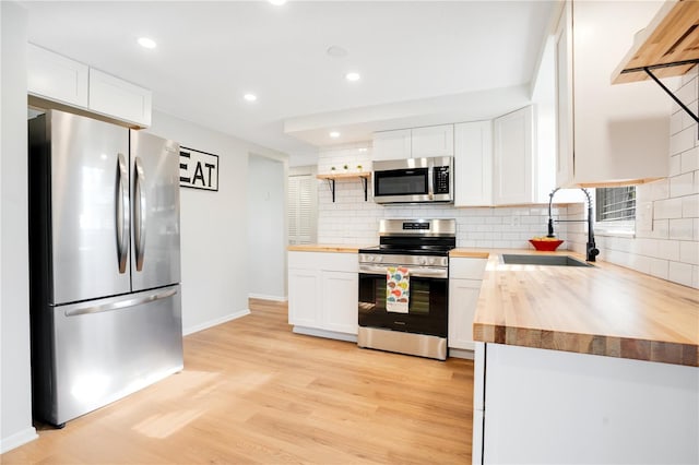 kitchen featuring sink, stainless steel appliances, butcher block countertops, light hardwood / wood-style floors, and white cabinets