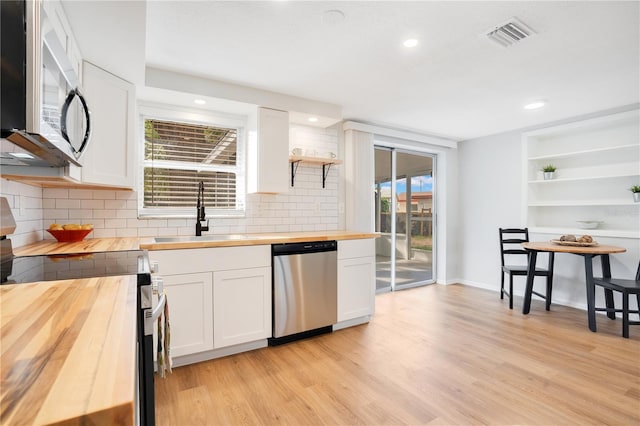 kitchen featuring butcher block counters, decorative backsplash, white cabinets, and appliances with stainless steel finishes