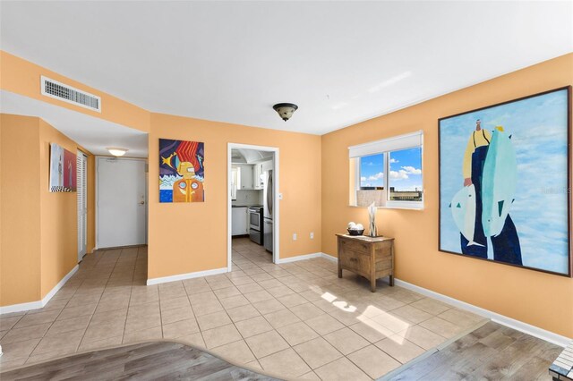 empty room with light tile patterned floors, visible vents, and baseboards