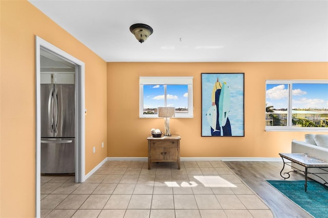 unfurnished room featuring light tile patterned floors, a healthy amount of sunlight, and baseboards