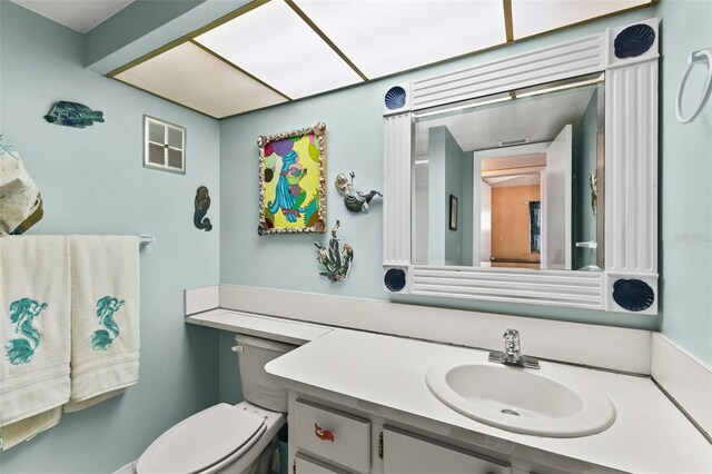 half bath with visible vents, toilet, and vanity