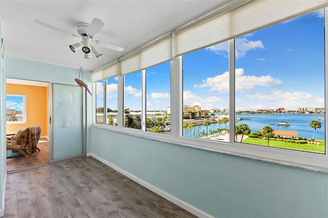 unfurnished sunroom with ceiling fan and a water view