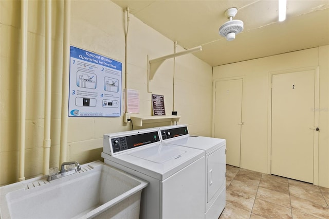 shared laundry area with light tile patterned floors, independent washer and dryer, and a sink