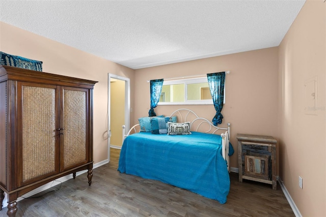 bedroom with a textured ceiling, baseboards, and wood finished floors