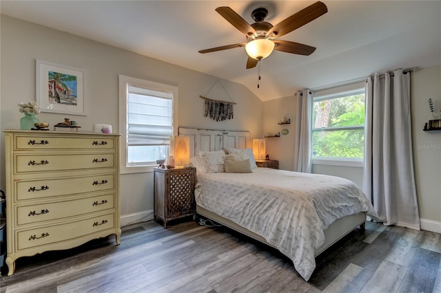 bedroom with vaulted ceiling, ceiling fan, multiple windows, and hardwood / wood-style flooring