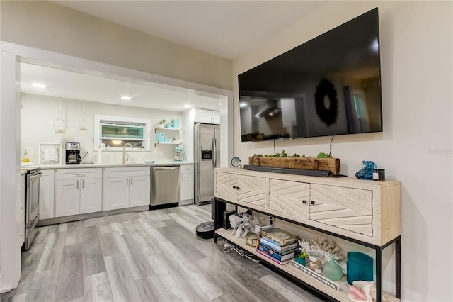 kitchen with light hardwood / wood-style flooring, sink, stainless steel appliances, and white cabinets