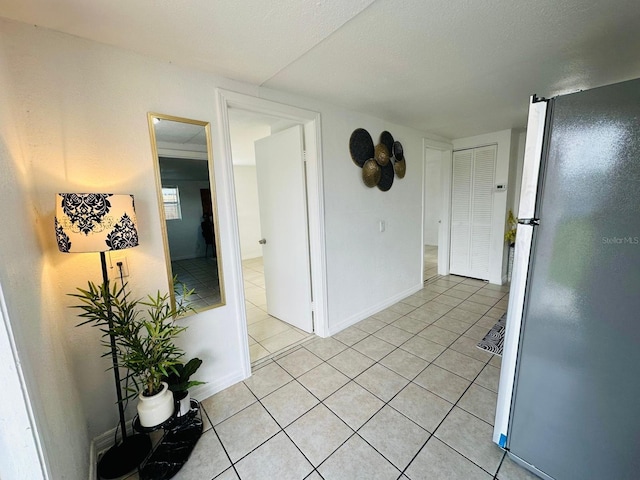 hallway with a textured ceiling and light tile patterned floors