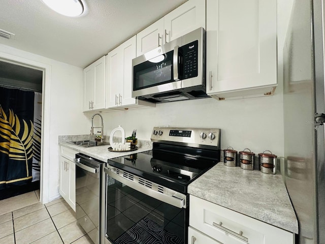 kitchen with appliances with stainless steel finishes, a textured ceiling, white cabinetry, and sink