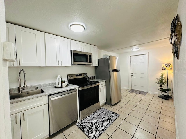 kitchen with a textured ceiling, sink, stainless steel appliances, and white cabinets