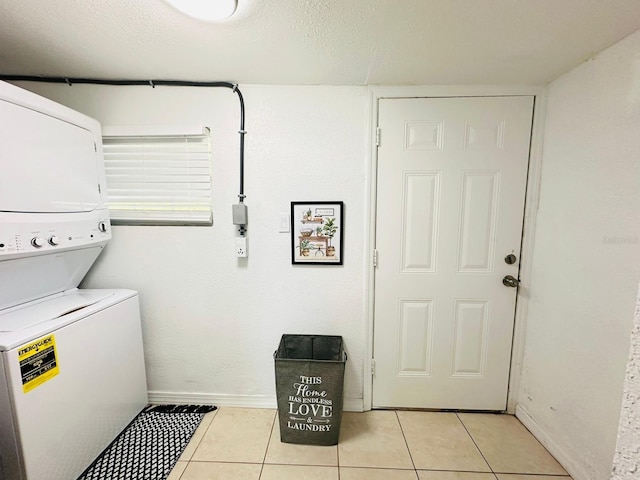 clothes washing area with a textured ceiling, stacked washer / drying machine, and light tile patterned floors