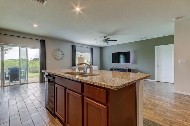 kitchen with light hardwood / wood-style flooring, sink, plenty of natural light, and an island with sink