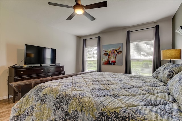 bedroom with multiple windows, light hardwood / wood-style floors, and ceiling fan