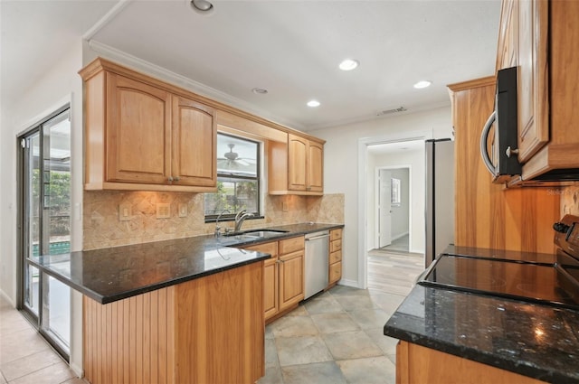 kitchen with dark stone counters, backsplash, kitchen peninsula, sink, and appliances with stainless steel finishes