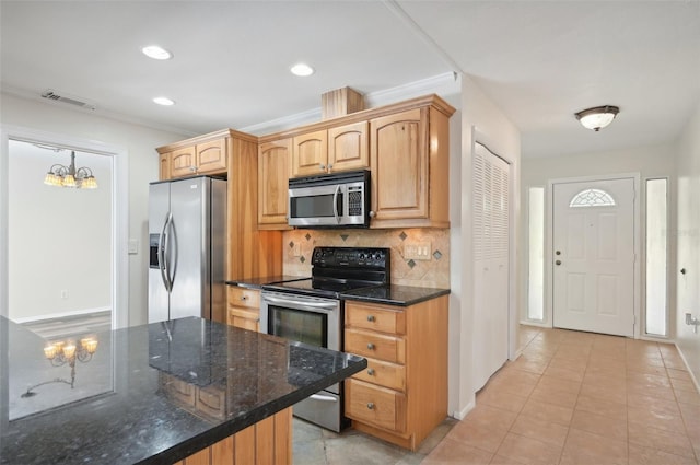 kitchen with ornamental molding, stainless steel appliances, dark stone countertops, and decorative backsplash