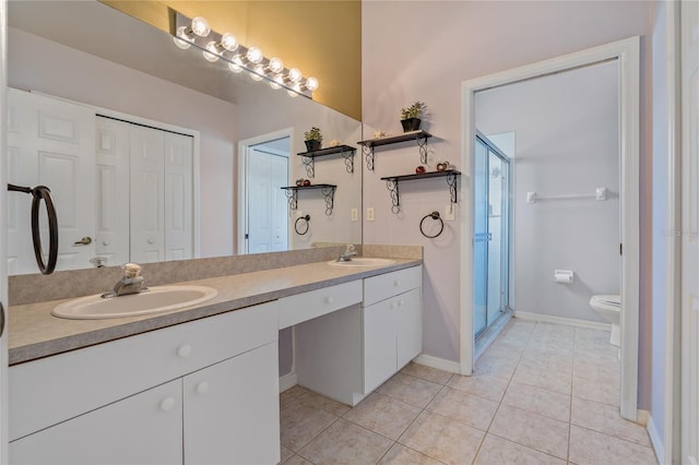 bathroom featuring tile patterned flooring, toilet, a shower with door, and vanity